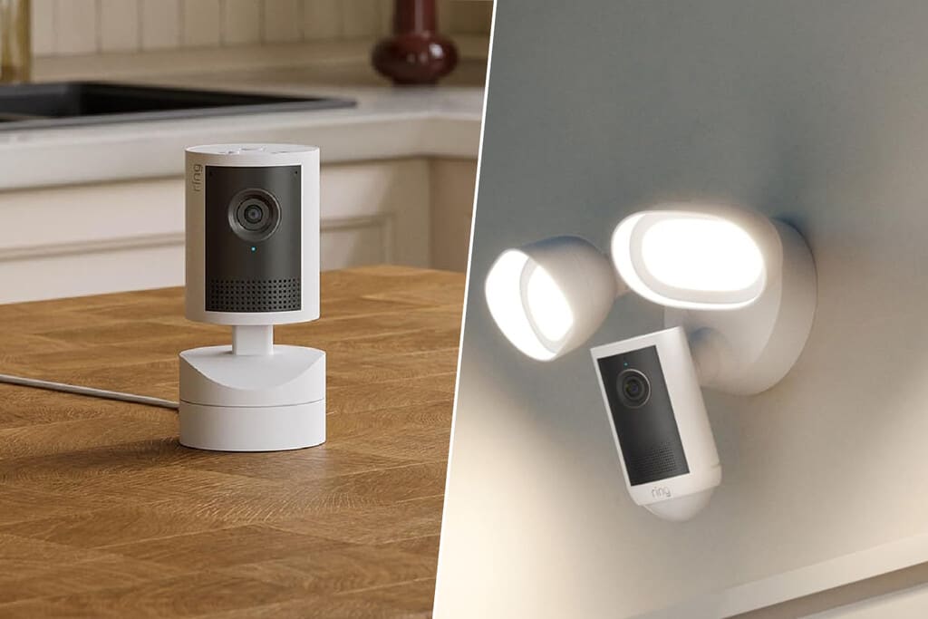 Una moderna cámara de seguridad Ring 4K con luces LED activadas, montada en una pared exterior de una casa, iluminando un jardín oscuro.