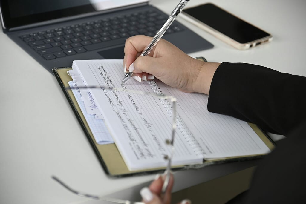 Persona trabajando en un escritorio moderno, con pantallas mostrando código y gráficos abstractos de IA, simbolizando la colaboración humano-IA.