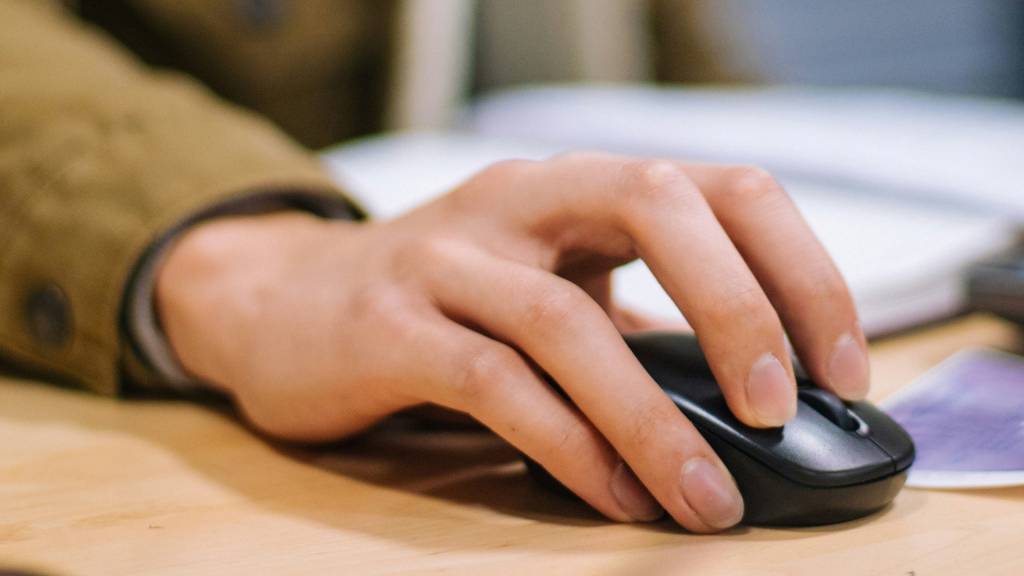 Un puntero de mouse resaltado de forma brillante sobre un fondo de pantalla de computadora con múltiples monitores.