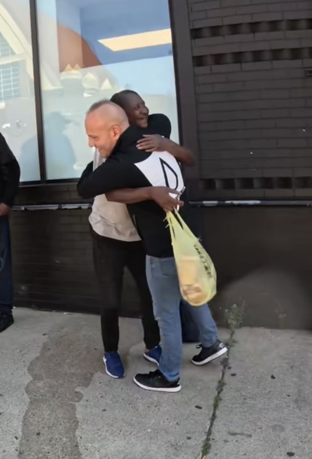 Smart Cups founder Chris Kanik embracing a recipient while distributing food during the community project with Josh Liljenquist.