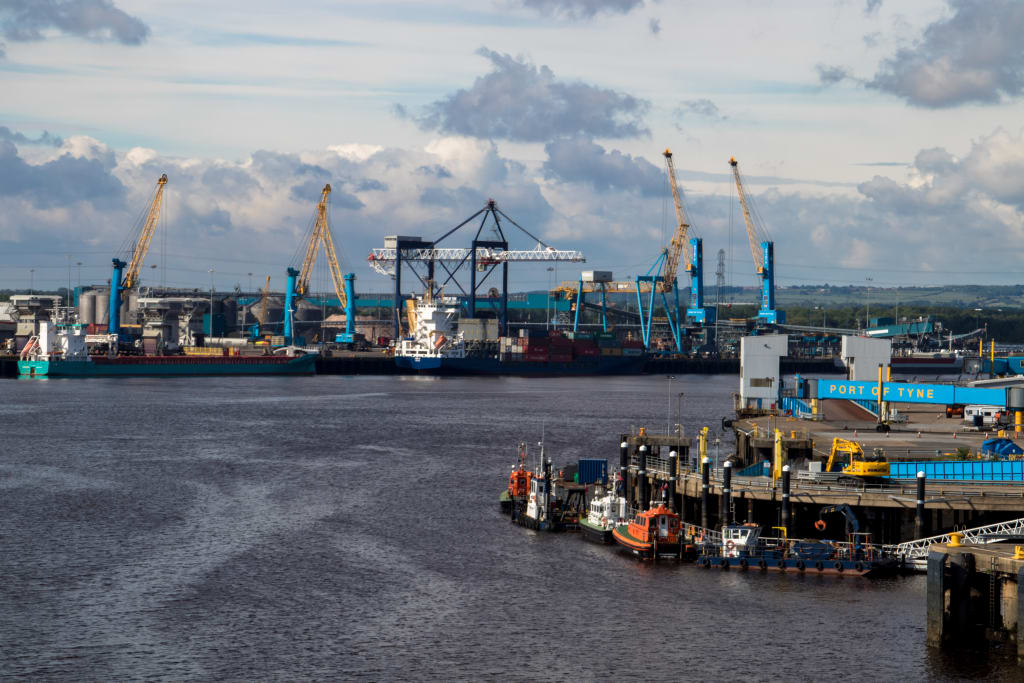 A view of Port of Tyne with several cranes, cargo ships, and industrial structures along the water, set under a cloudy sky, highlights the potential for green shipping innovations.