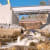 A river flows over rocky terrain with a concrete bridge under construction above it, embodying the National Highways commitment to low carbon infrastructure, while an older metal bridge stands in the background.