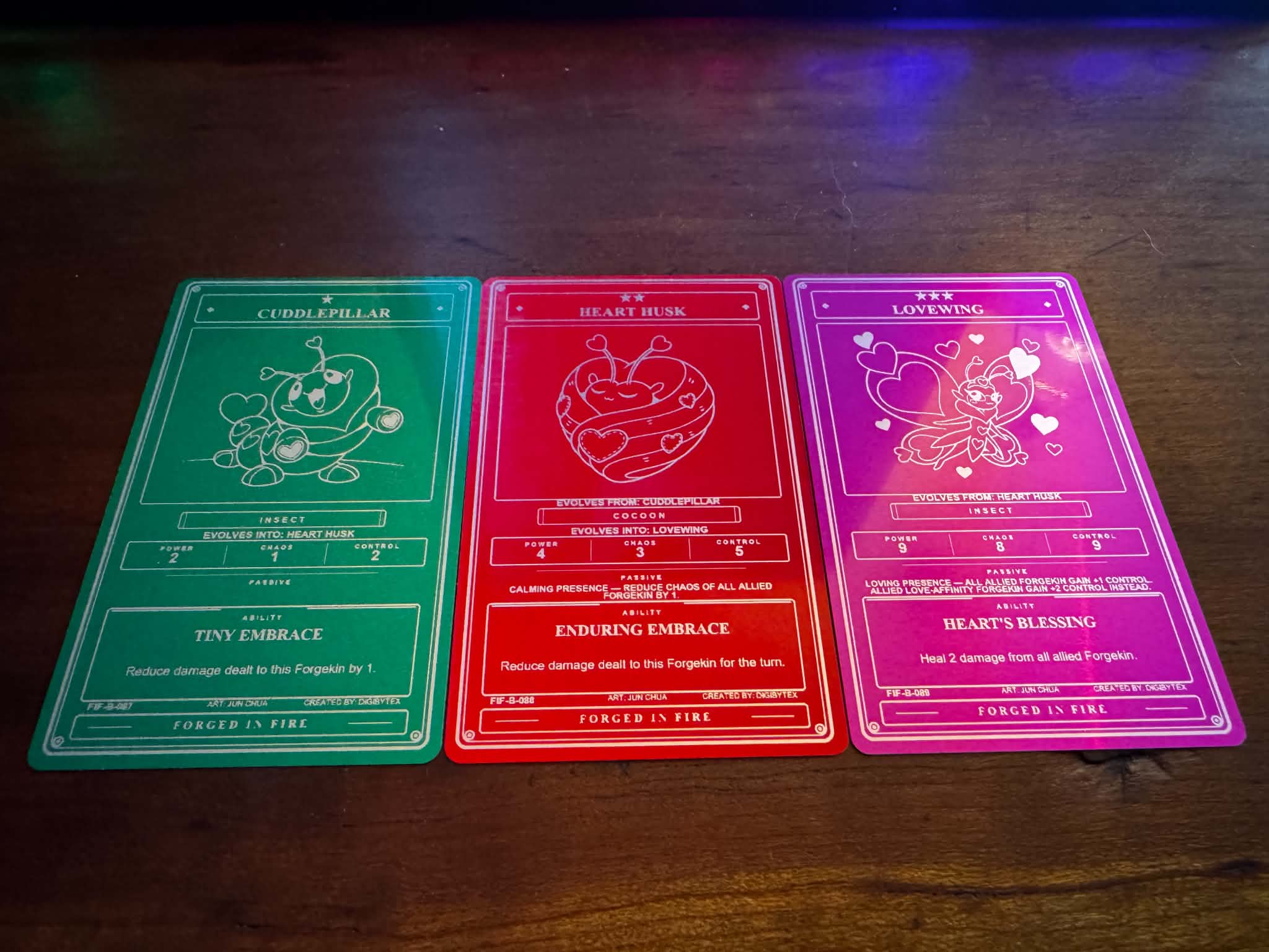 Love Evolution Line — Cuddlepillar, Heart Husk, and Lovewing engraved in green, red, and purple anodized aluminum.