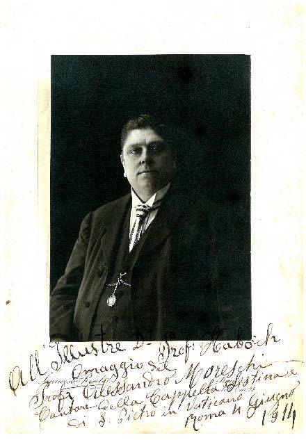 Sepia portrait of a heavy-set middle-aged Alessandro Moreschi in a dark suit, mounted on a card with a handwritten Italian dedication to Professor Haböck dated June 1914.