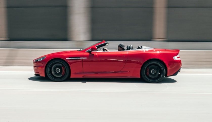 Man driving red sports car down highway