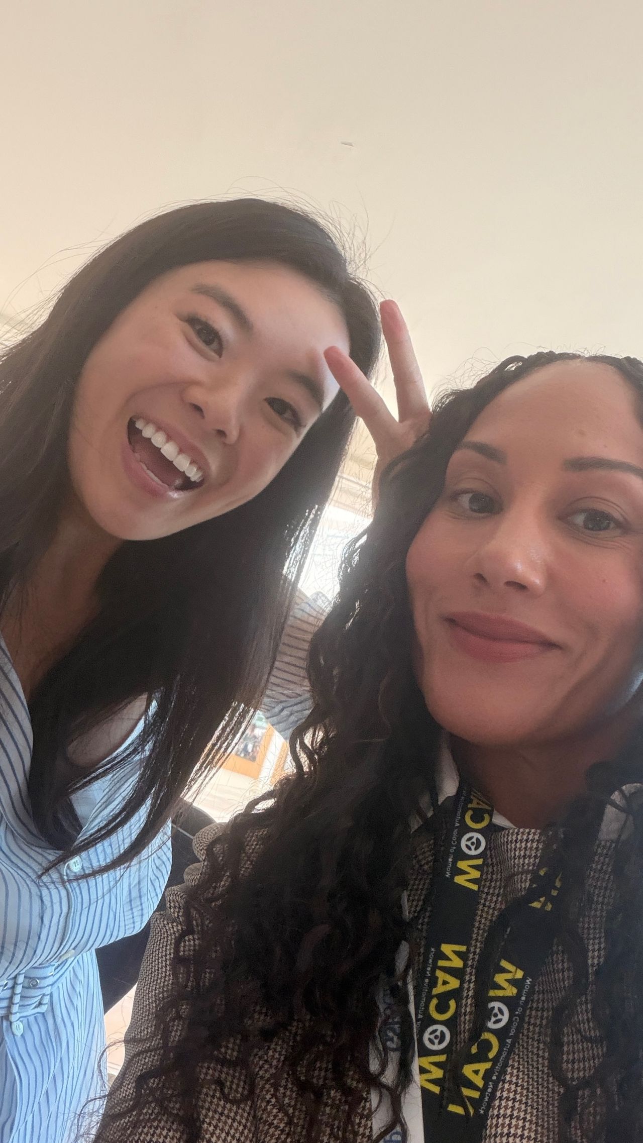 Two women smiling for a selfie, one with a WOCAN lanyard.