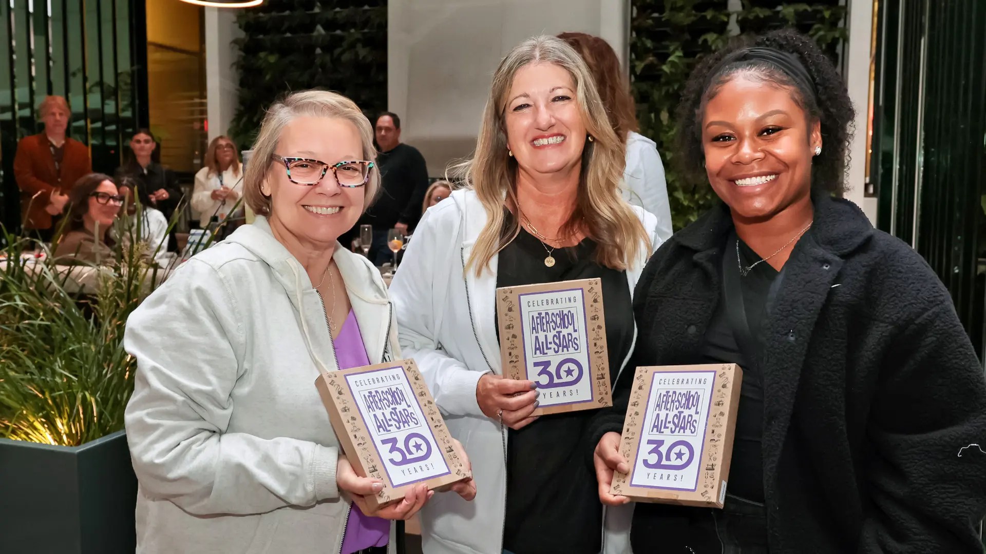 Three women holding frames and smiling together