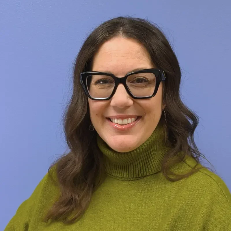 Woman wearing green turtleneck and glasses