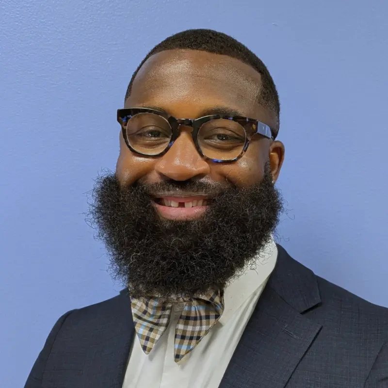 A man with a beard in a bow tie and glasses smiling