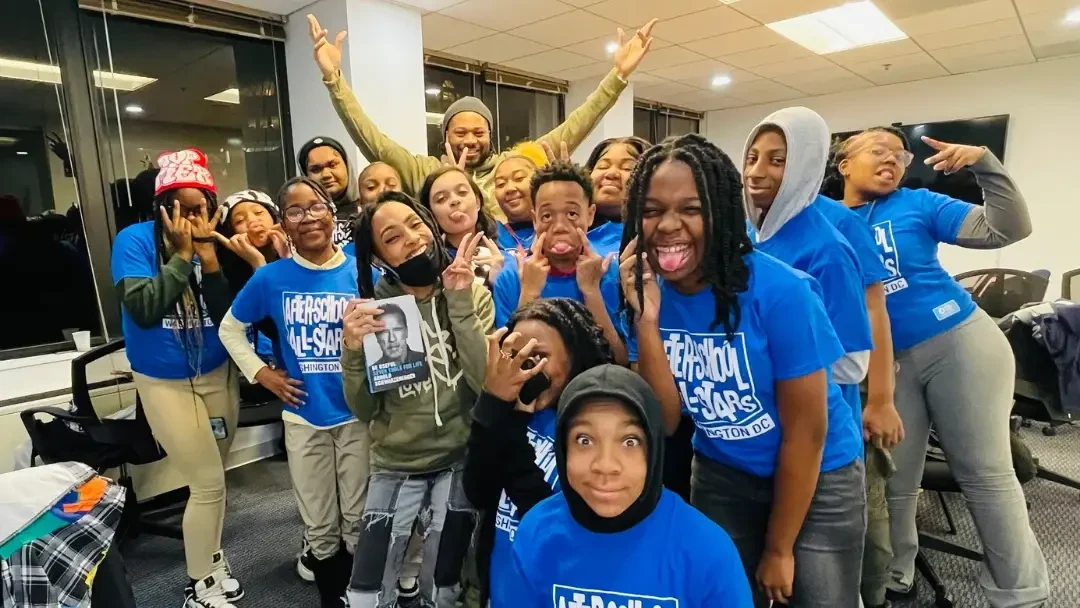 A large group of ASAS DC students wearing matching blue shirts pose together and smile