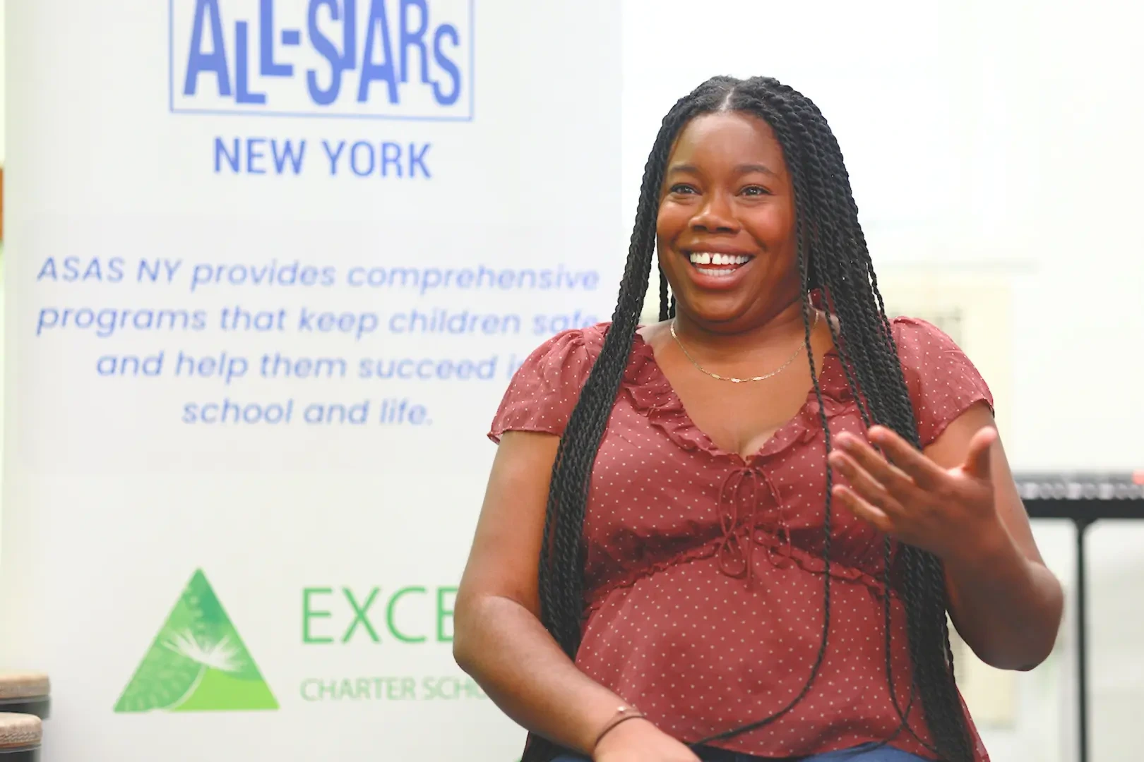 Woman with red shirt stands in front of an ASAS logo