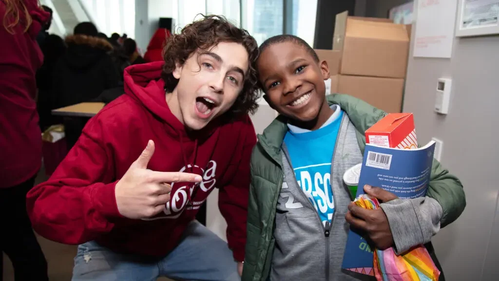 A man in a red hoodie with a boy in a grey sweater and blue shirt