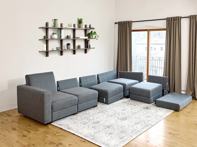 Stop motion video of grey modular sofa bed being assembled.