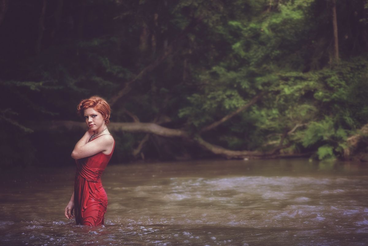 Woman with red dress in river and forest