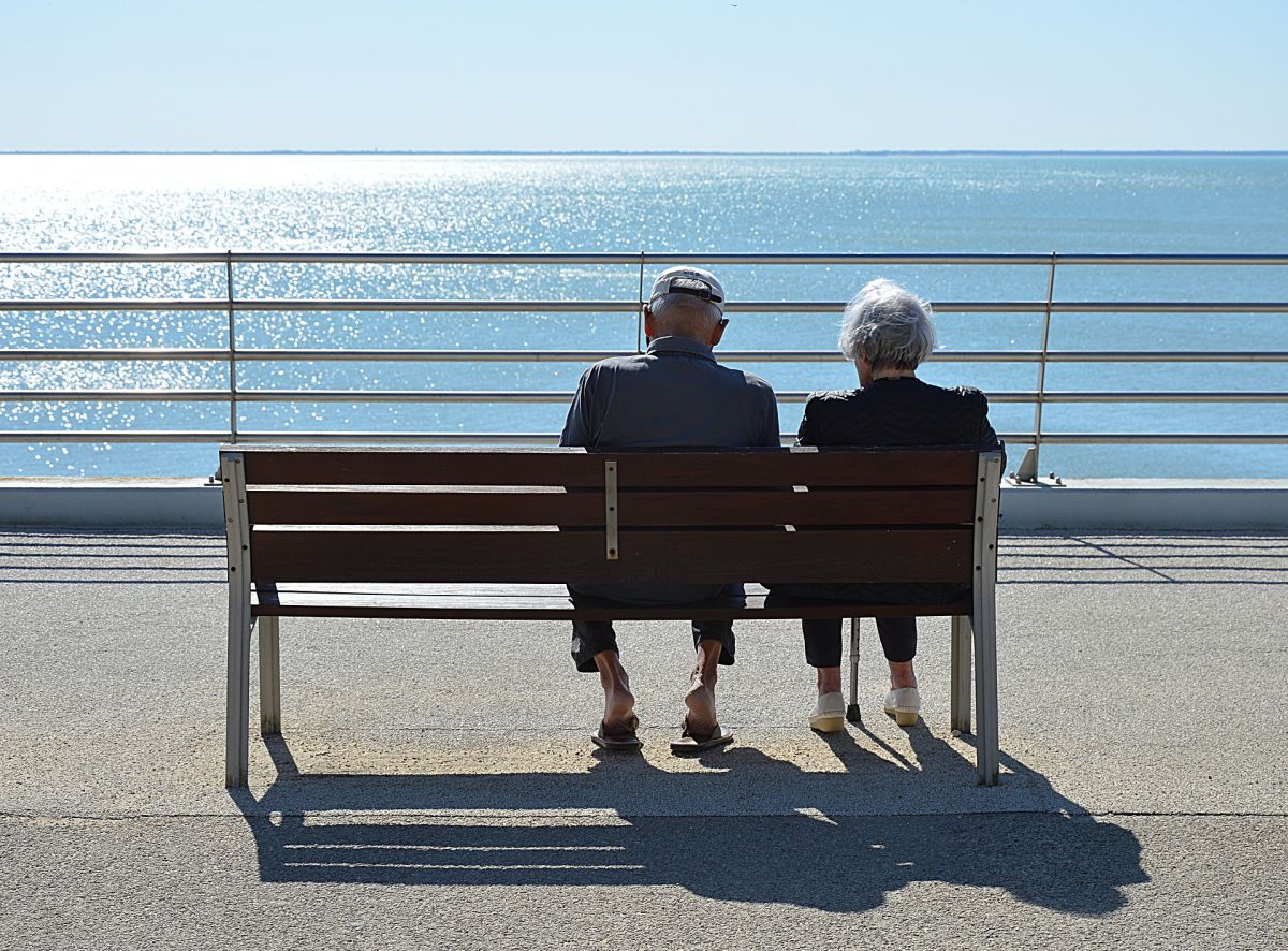 Old couple sitting on a bench next to a lake