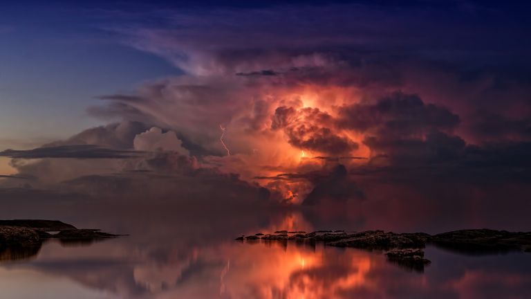 Sunset on mirroring ocean with orange clouds