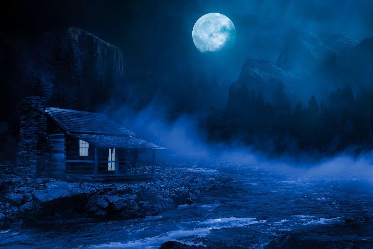 Moon shining during night over a hut near the river