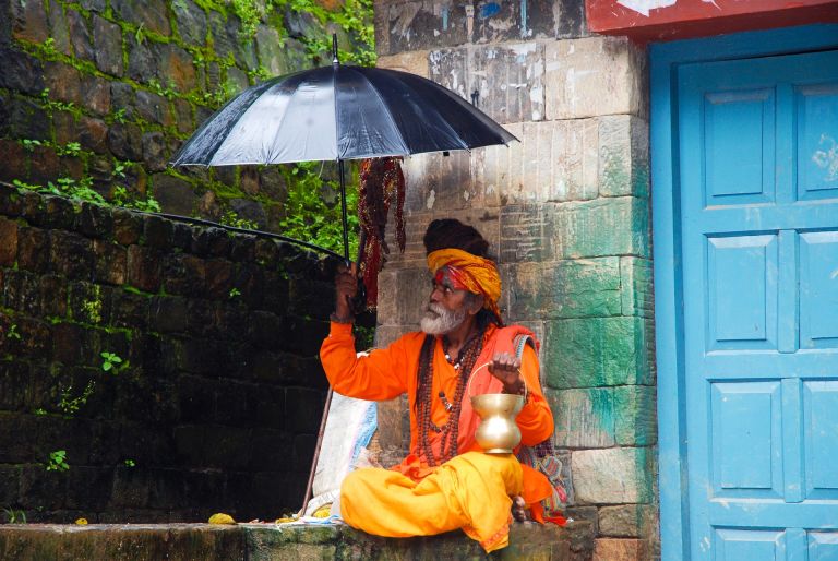 Guru with red-orange dress and umbrella