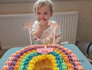 Celebration cake: A baby is sitting in front of a cake