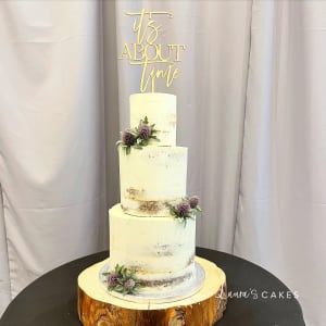 Wedding cake: A white cake with a gold topper and a purple flower