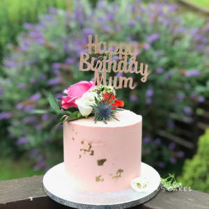 Celebration cake: A pink cake with a gold happy birthday sign on top
