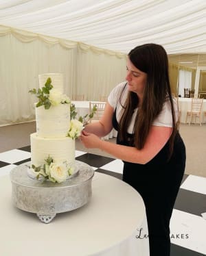 Wedding cake: A woman is cutting a cake on a table