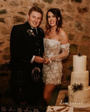 Wedding cake: A man and woman standing next to a cake