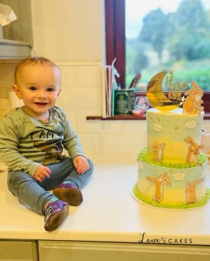 Celebration cake: A baby sitting on a counter with a cake