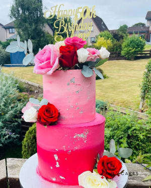 Celebration cake: A pink cake with roses and a gold sign that says happy birthday