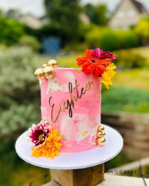 Celebration cake: A pink cake with gold and flowers on top