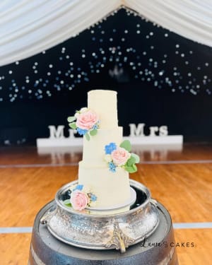 Wedding cake: A white wedding cake with pink and blue flowers on top