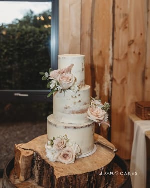Wedding cake: A white wedding cake with pink flowers on a tree stump