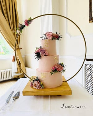 Wedding cake: A pink cake with flowers on a wooden stand
