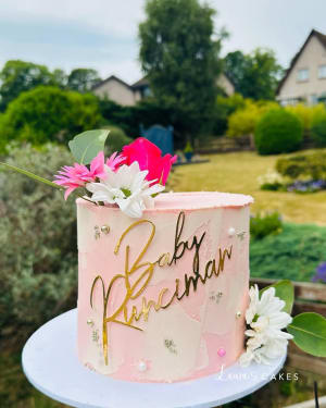 Celebration cake: A pink cake with gold lettering and flowers on top