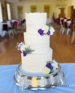 Wedding cake: A white cake with purple flowers on a silver stand