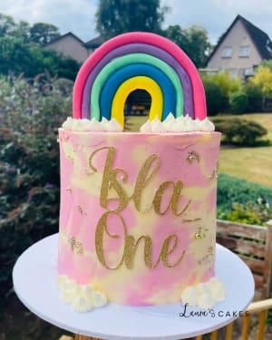 Celebration cake: A pink and gold cake with a rainbow on top