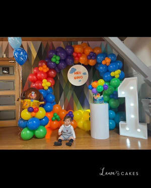 Celebration cake: A baby is sitting on the floor with balloons