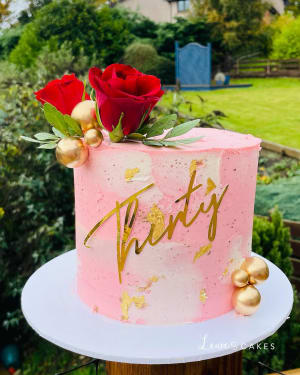 Celebration cake: A pink and gold cake with a rose on top