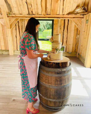 Wedding cake: A woman standing next to a barrel with a cake on it