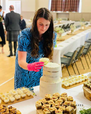 Wedding cake: A woman in a blue dress is cutting a cake