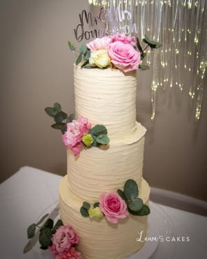 Wedding cake: A white cake with pink flowers and greene on top