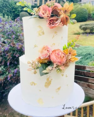 Wedding cake: A white cake with gold leaf and flowers on top