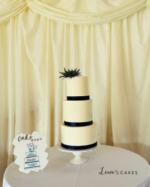Wedding cake: A white cake with black ribbon and a small pine