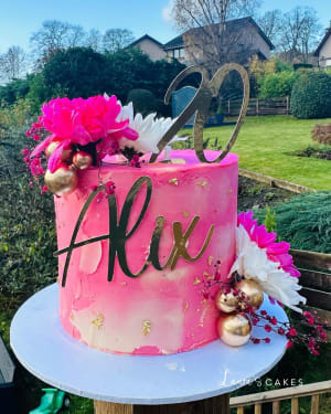 Celebration cake: A pink cake with gold and pink flowers on top