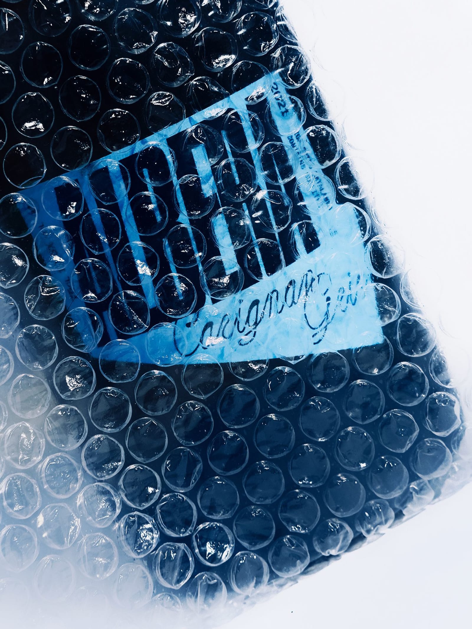 Albera Carignan Gris wine bottle wrapped in black bubble wrap with the light blue label partially visible through the plastic
