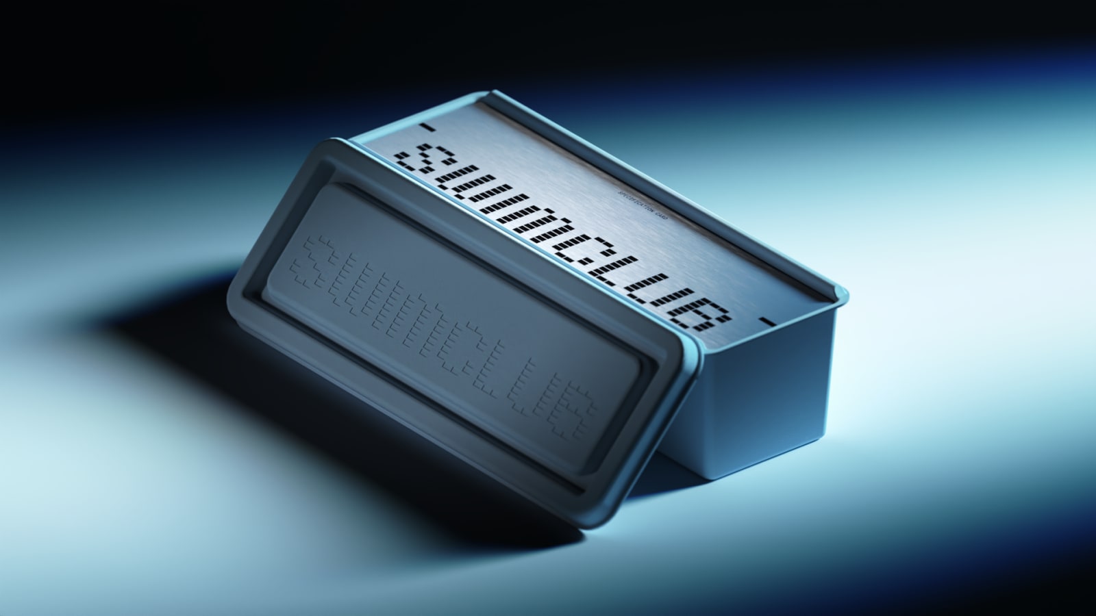 Gray rectangular device with braille dots on top surface and control panel, tilted perspective on gradient background