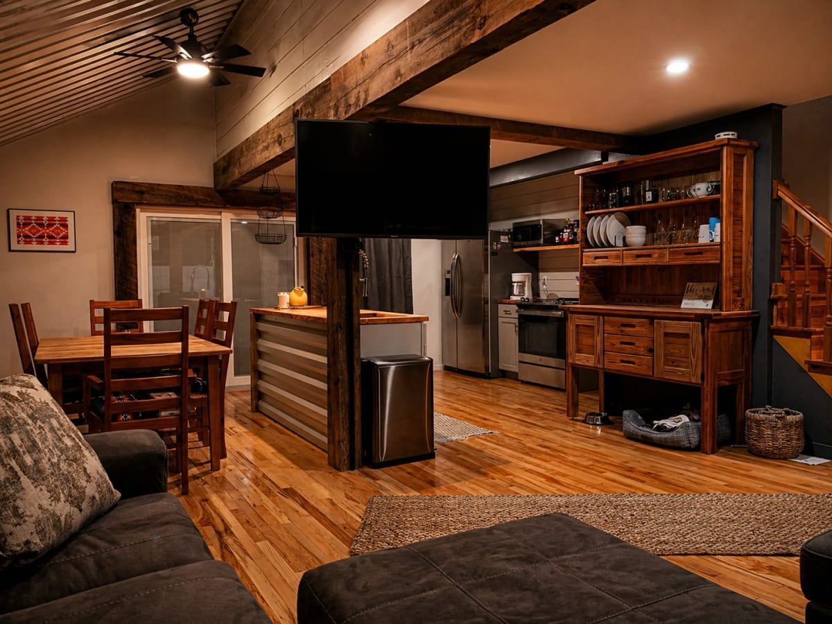 Open camp kitchen and living area with metal ceiling, wood counters, rough-sawn beams, and freestanding hutch