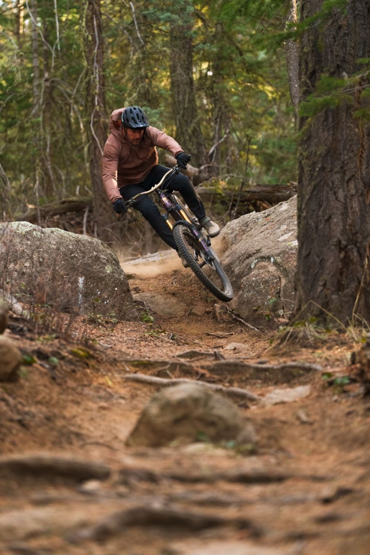 action shot of the trailcat lt moving towards the camera with a rider on board leaning slightly off of a large rock and catching some air
