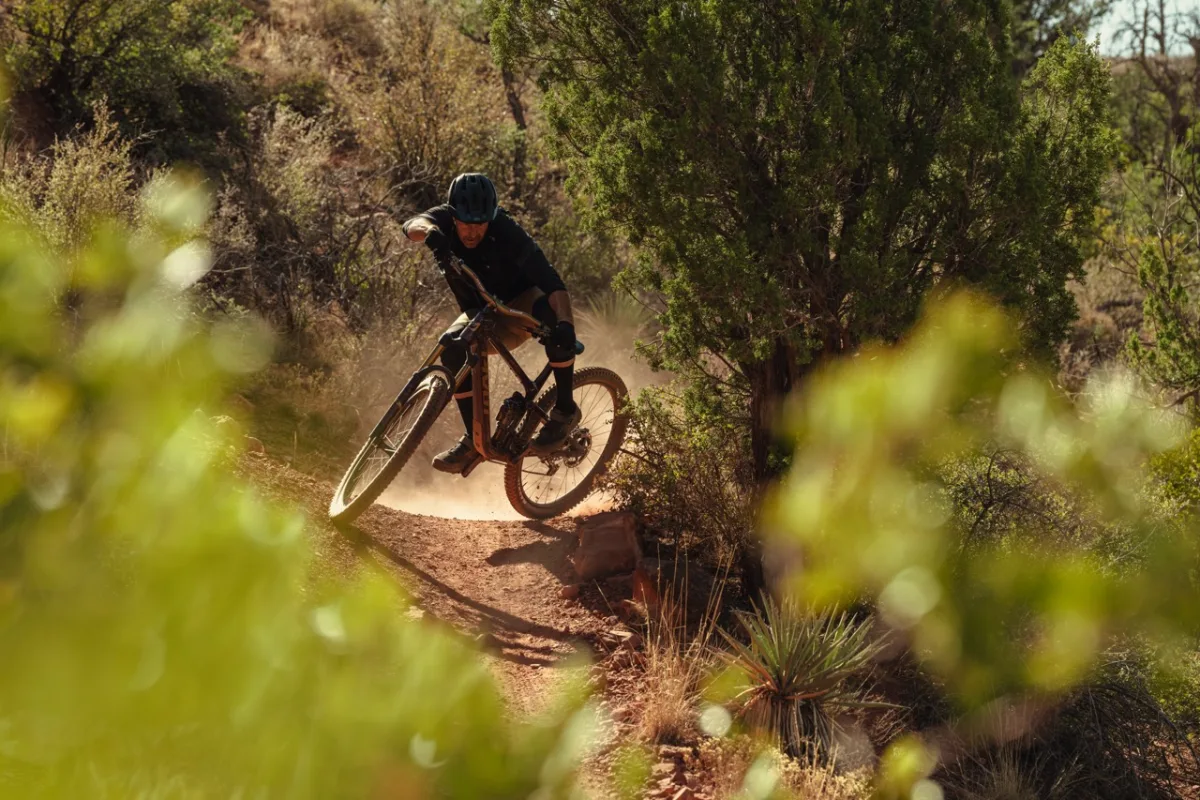 rider skidding across an off camber corner on the trailcat lt facing the camera with the bike moving sideways across the ground and the rider twisted to keep balance facing forward down the trail