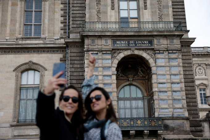 Du khách check in khung cửa sổ nơi nhóm trộm đã đột nhập vào bảo tàng Lourve: Ảnh: Reuters